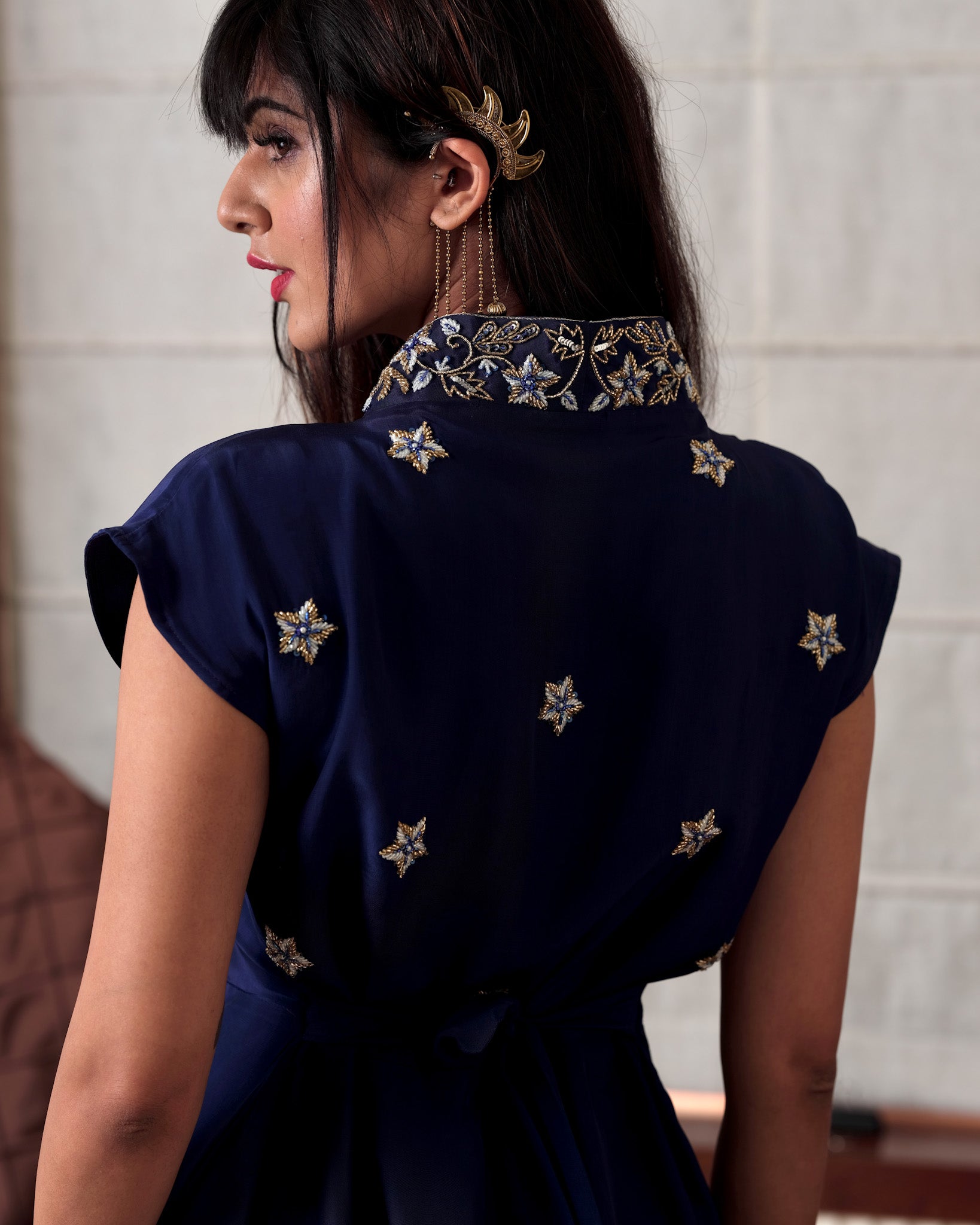 Woman wearing a navy blue dress with star patterns, indoors.