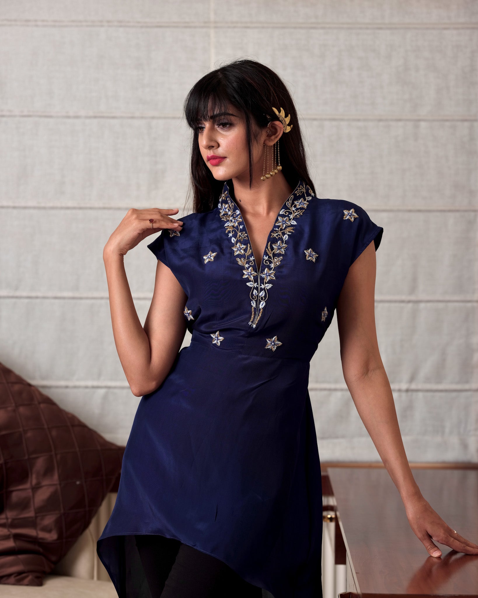 Woman wearing a navy blue dress with star patterns in an indoor setting