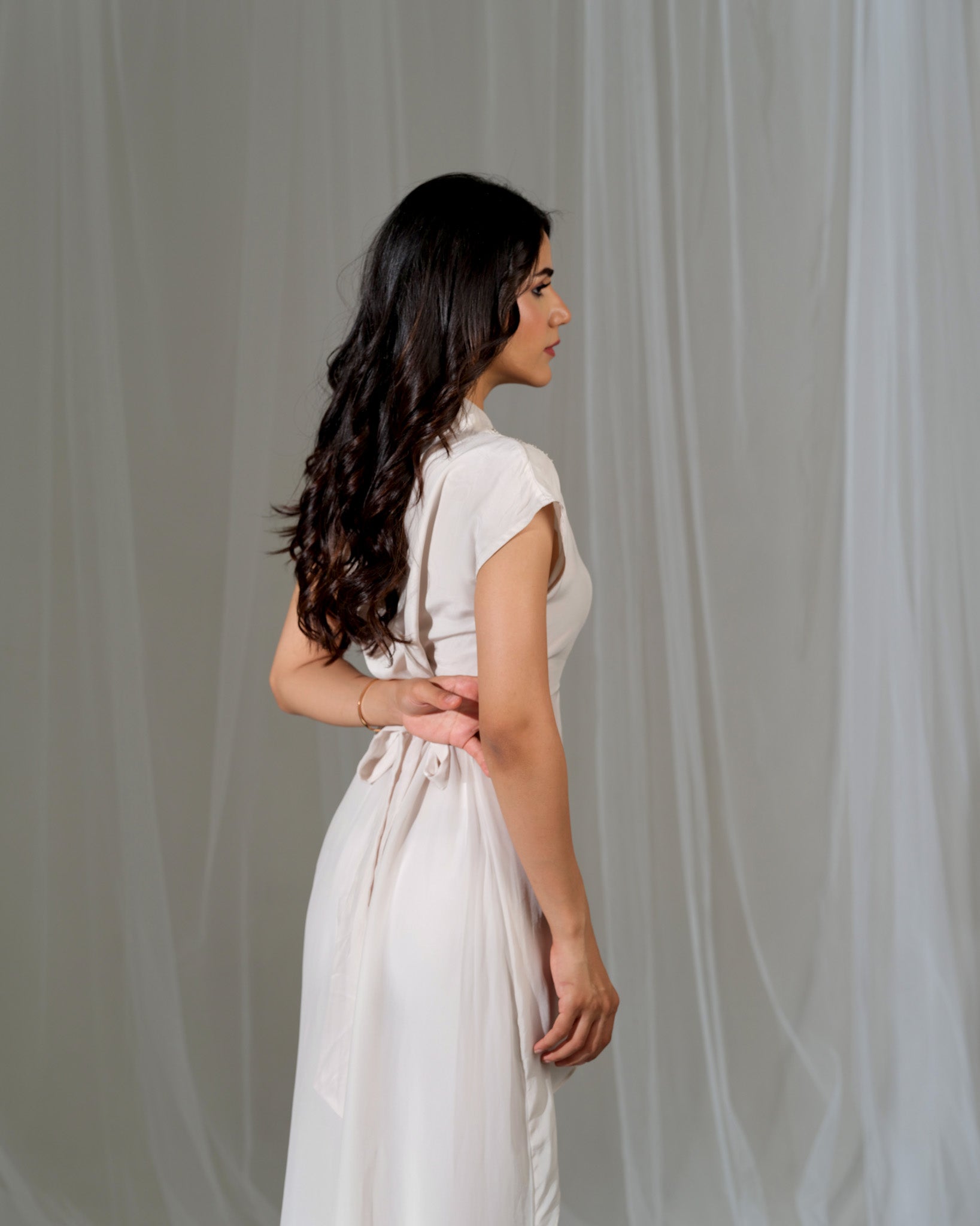 Woman wearing a white dress against a gray background