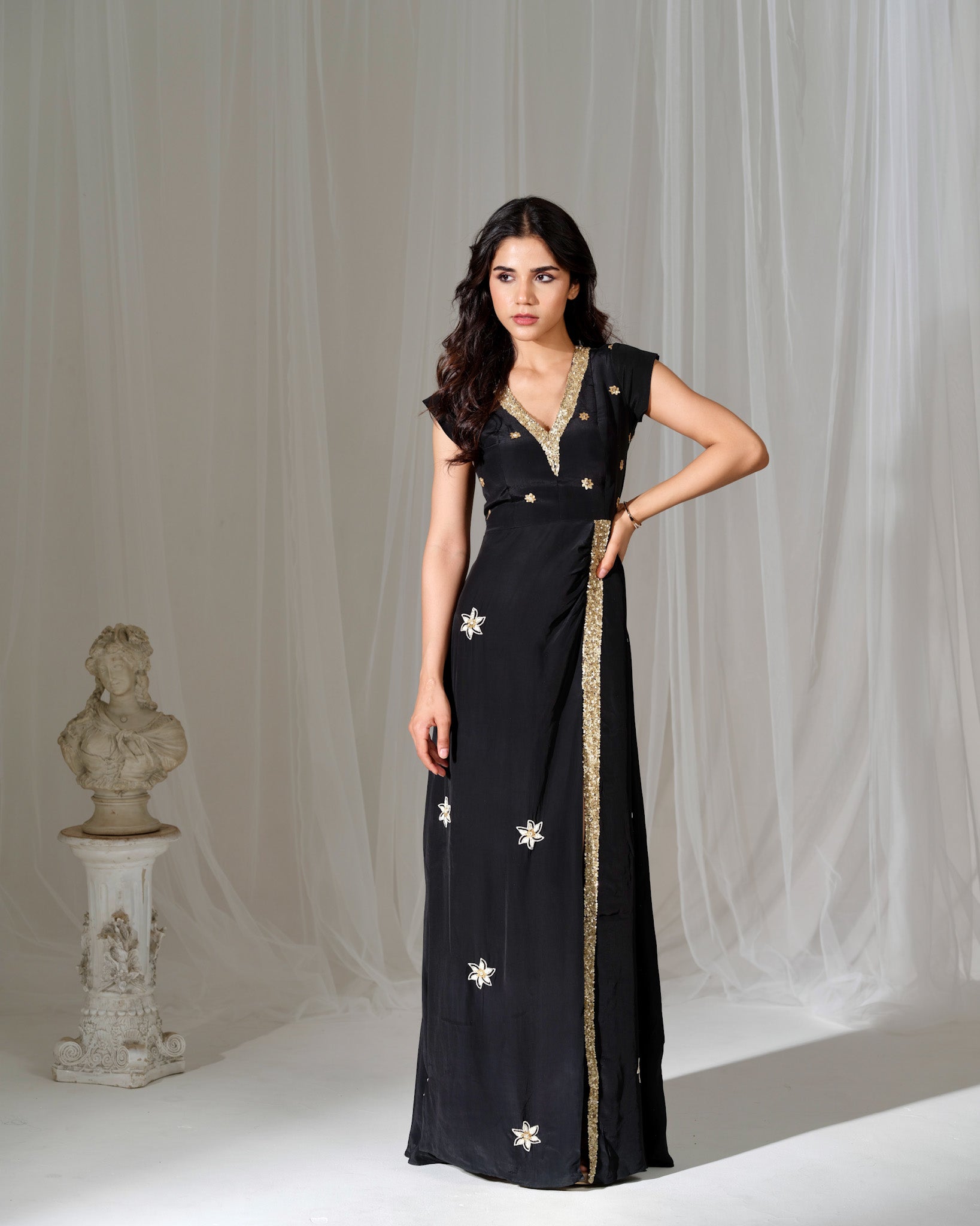 Woman wearing a black dress with floral patterns in a studio setting