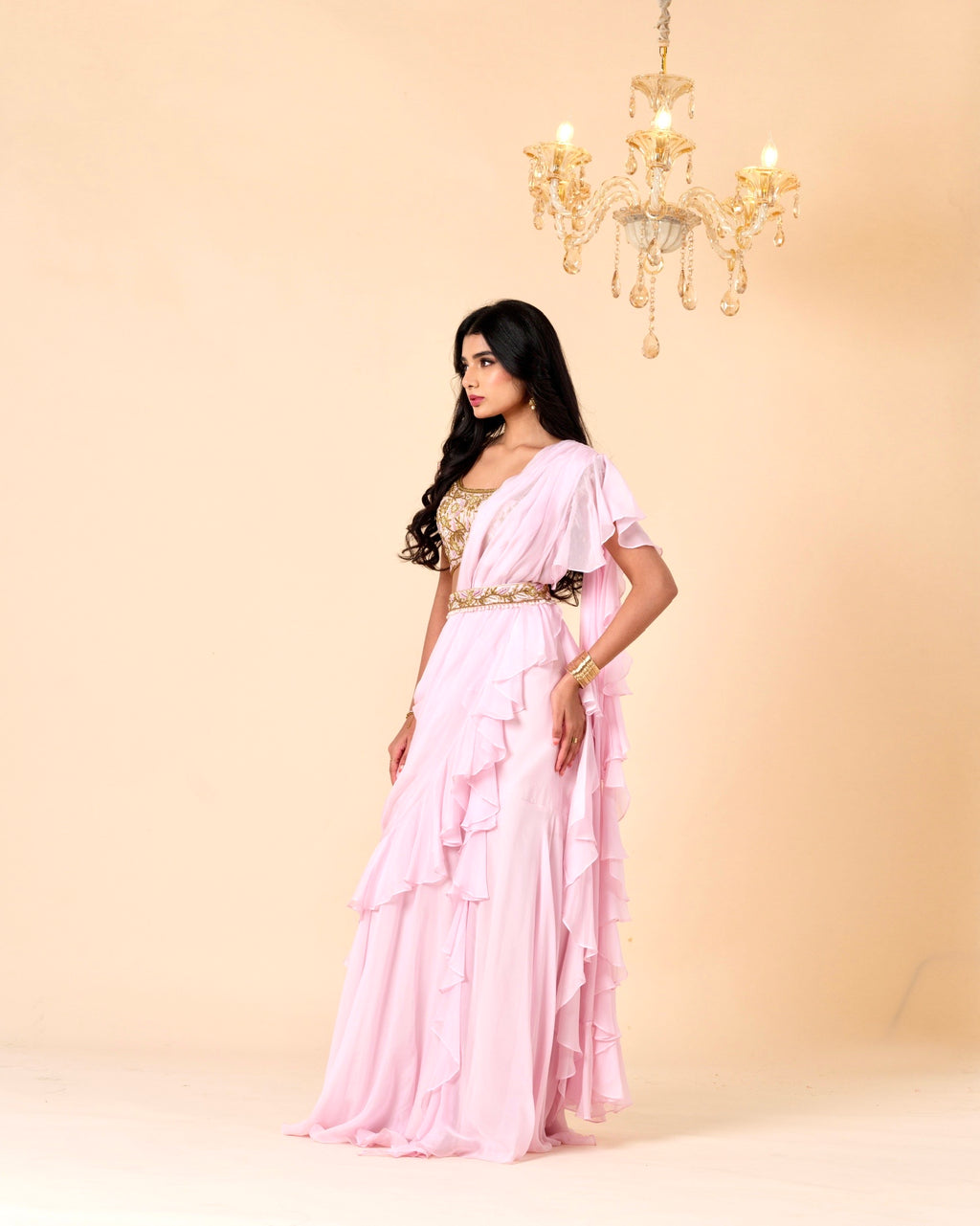 Woman in a pink saree with a gold blouse against a beige background