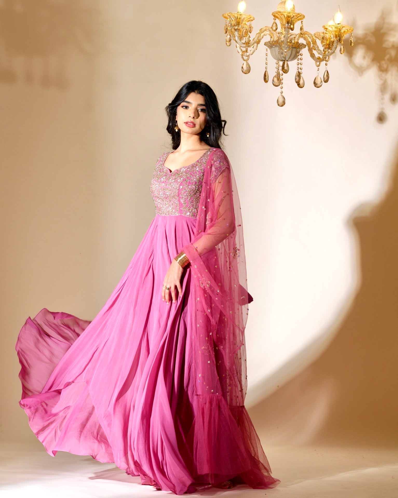 Woman in a pink saree with a chandelier in the background