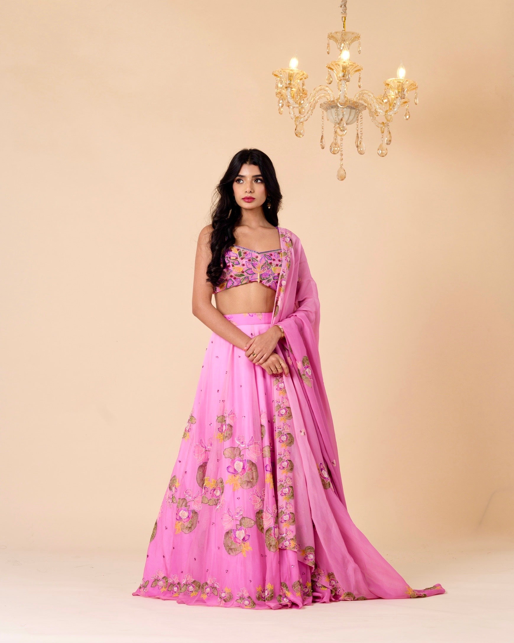 Woman wearing a pink traditional outfit with floral patterns against a beige background