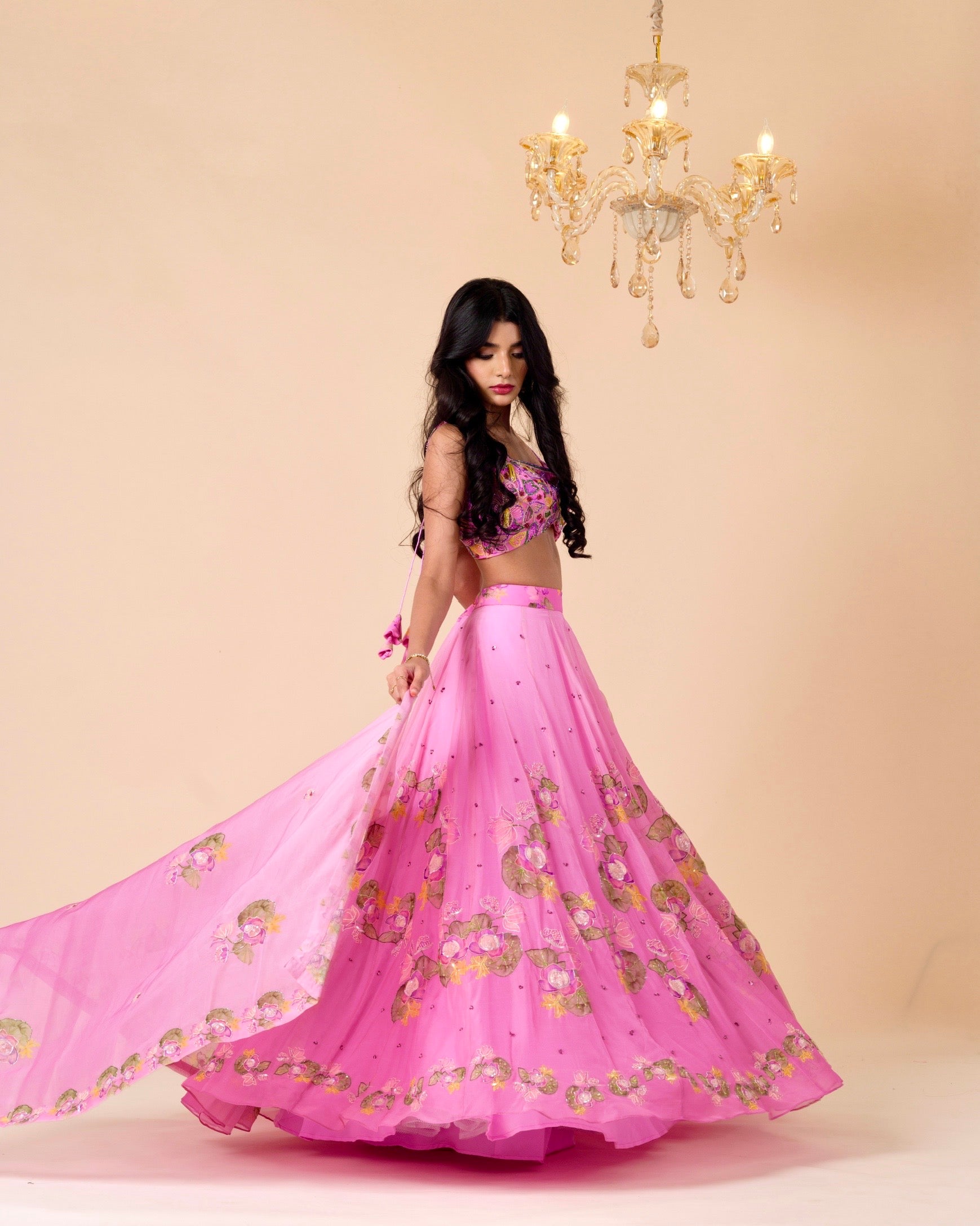 Woman wearing a pink traditional outfit with floral patterns against a beige background