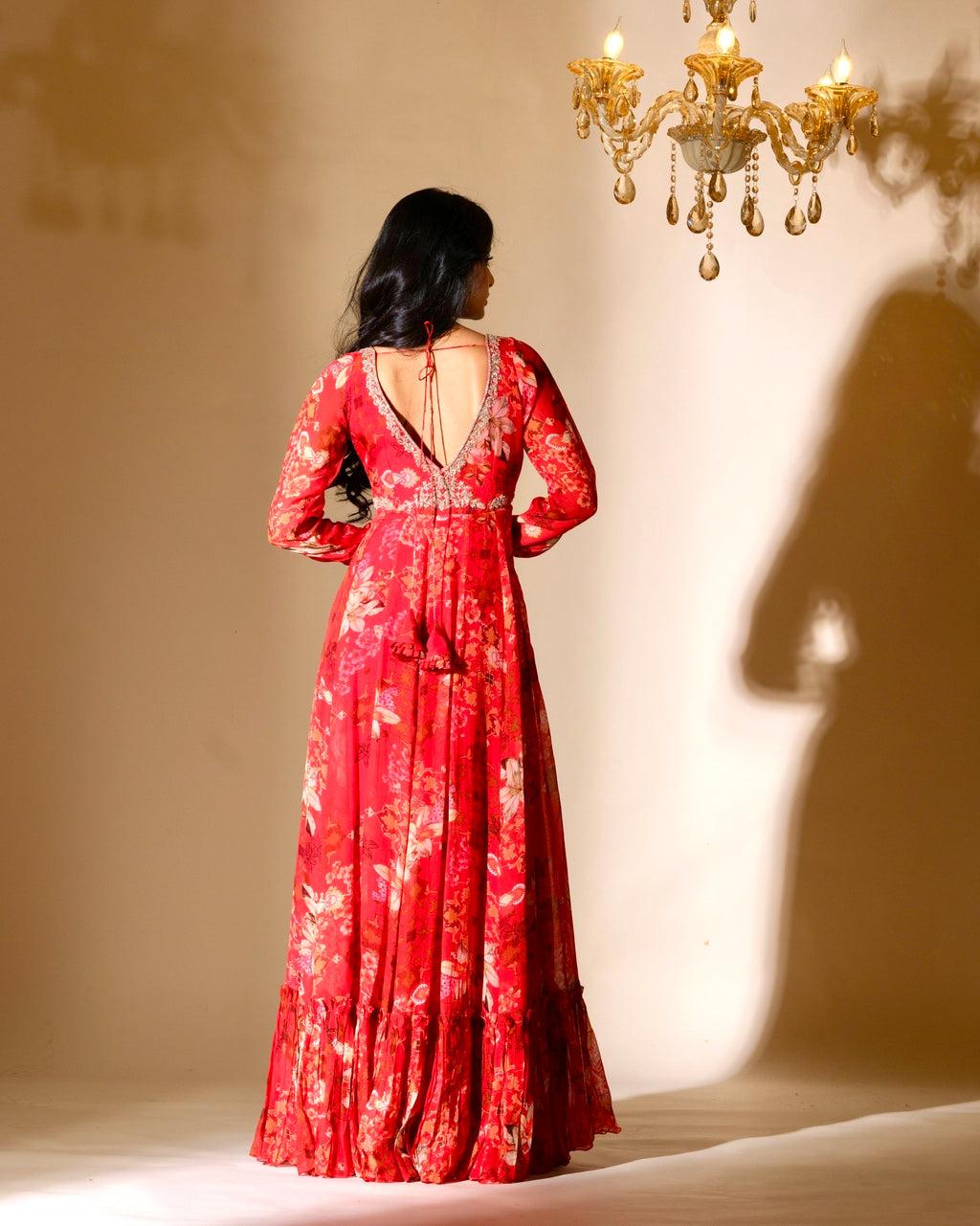 Woman wearing a red floral dress with a chandelier in the background