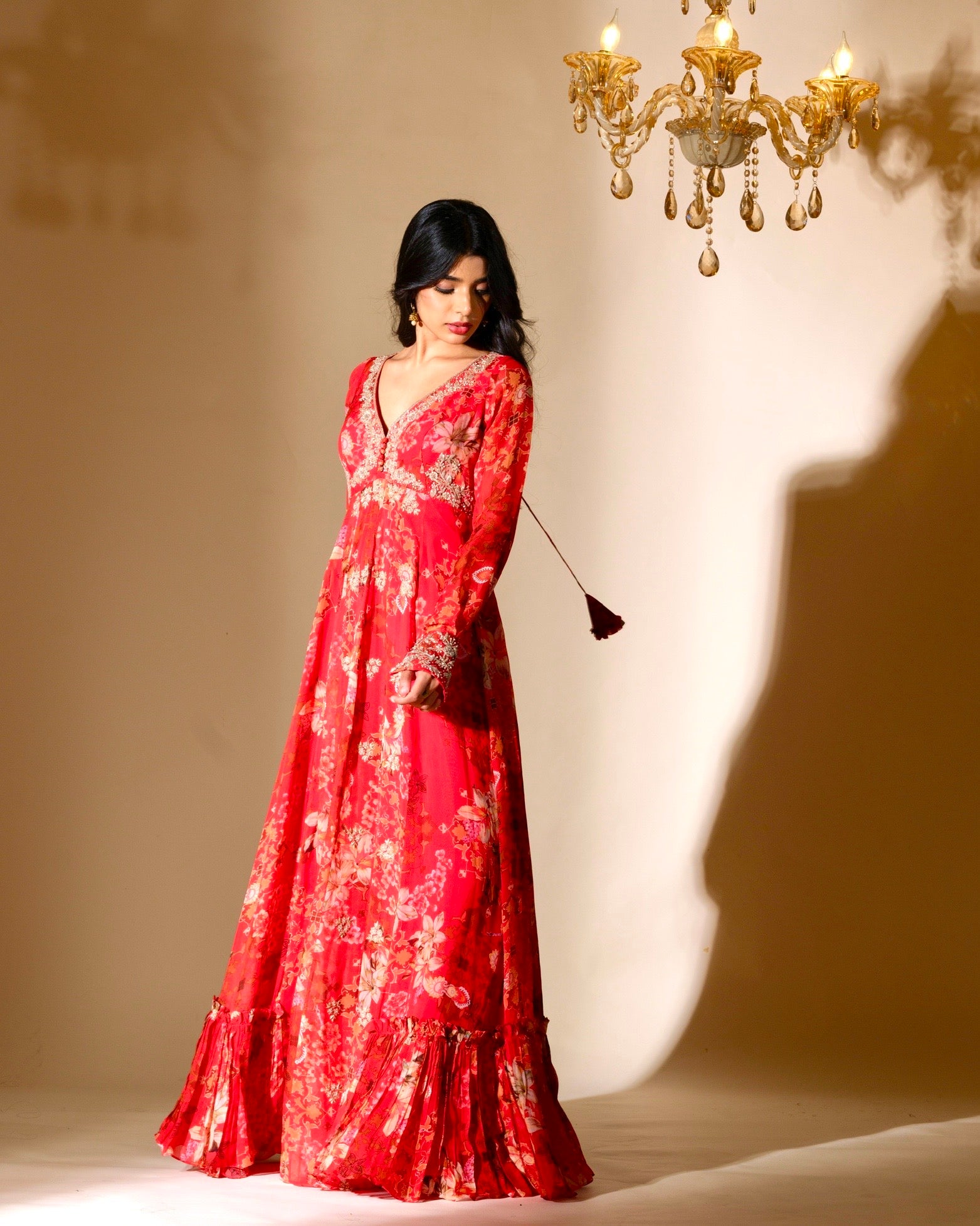 Woman in a red floral dress standing in front of a chandelier