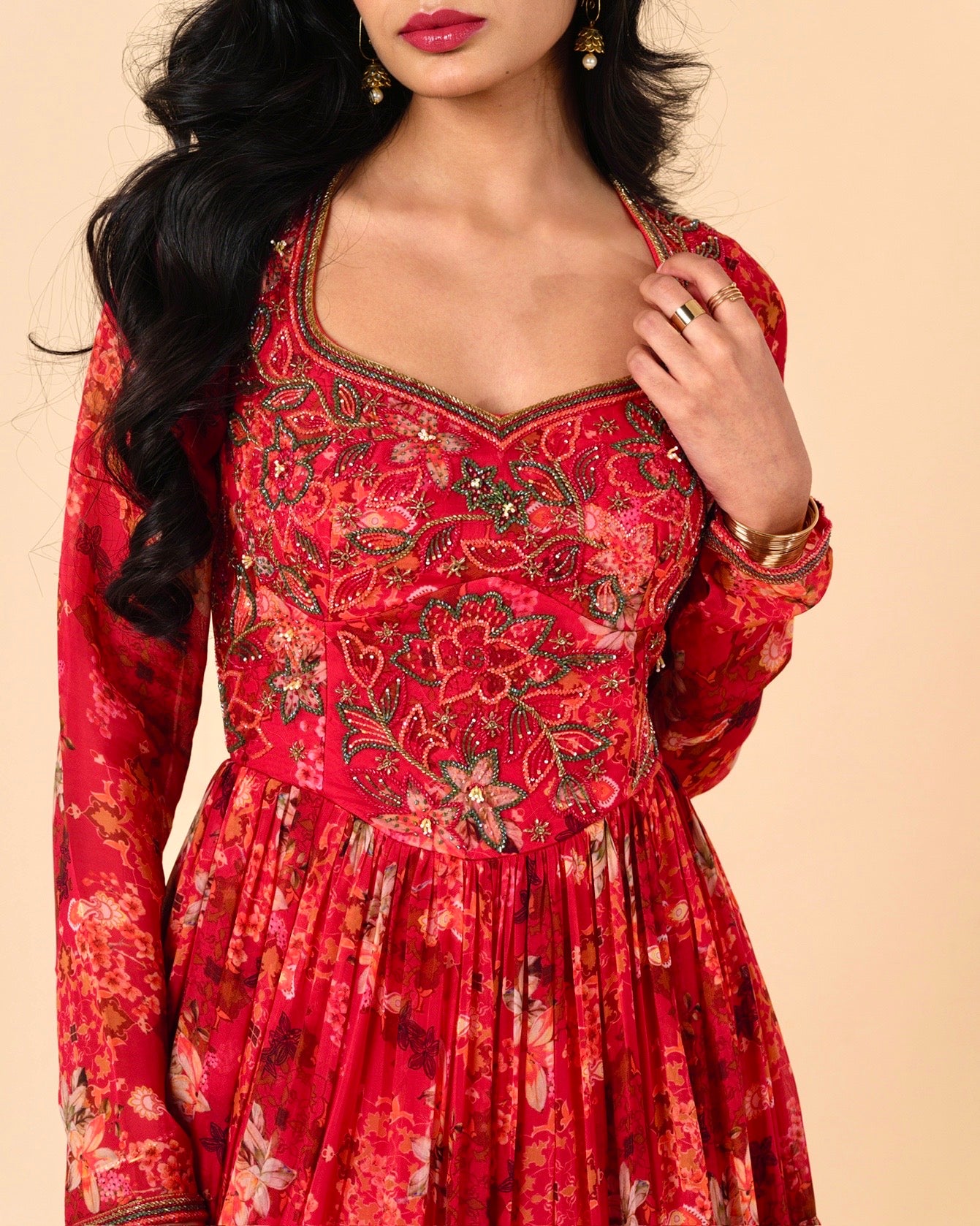 Red patterned dress worn by a model on a beige background