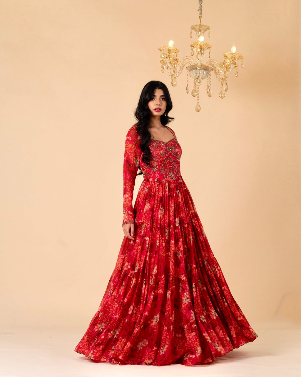 Woman wearing a red floral dress with a chandelier in the background