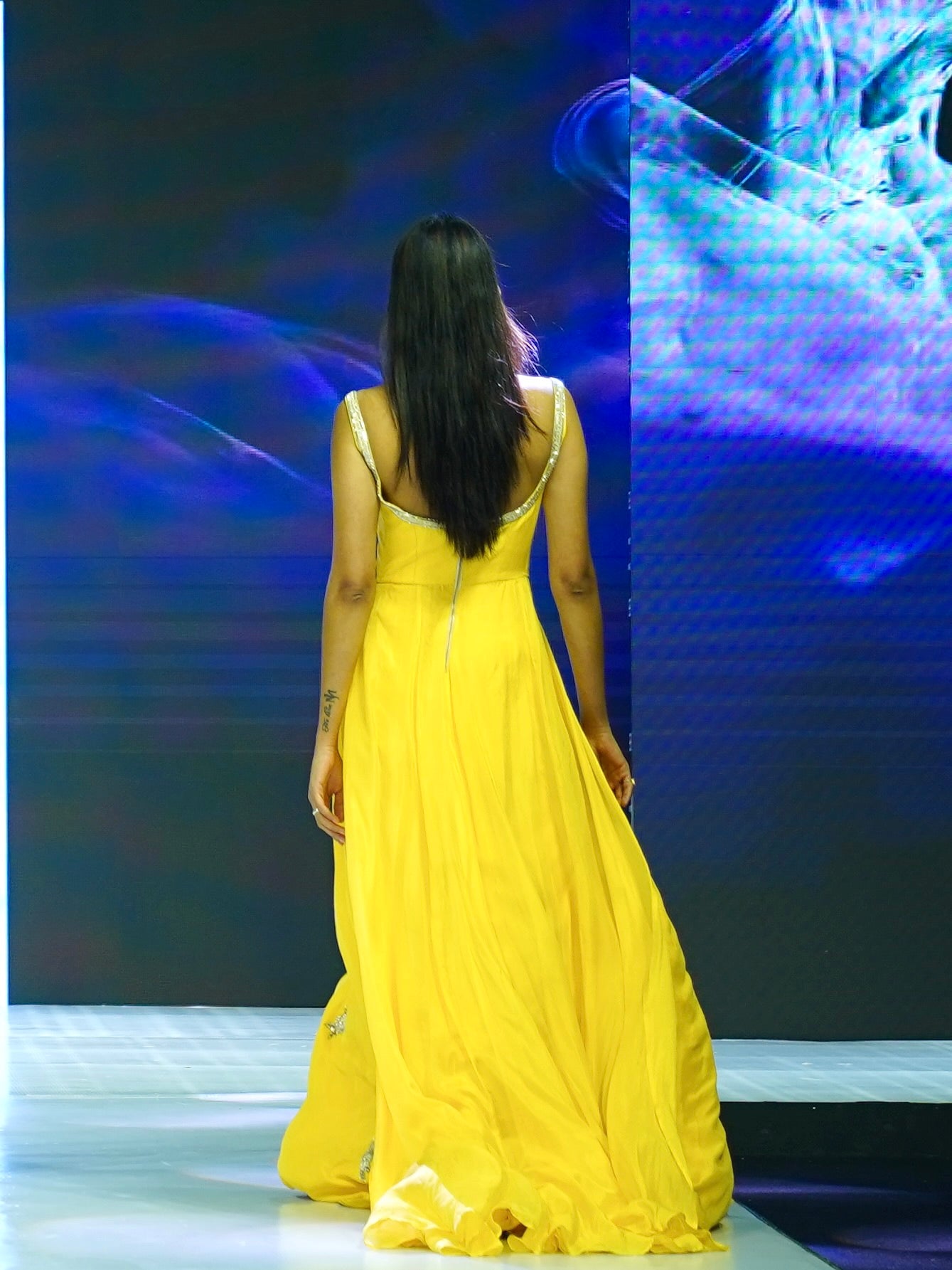 Woman in a yellow dress standing on a stage with a blue and white abstract background