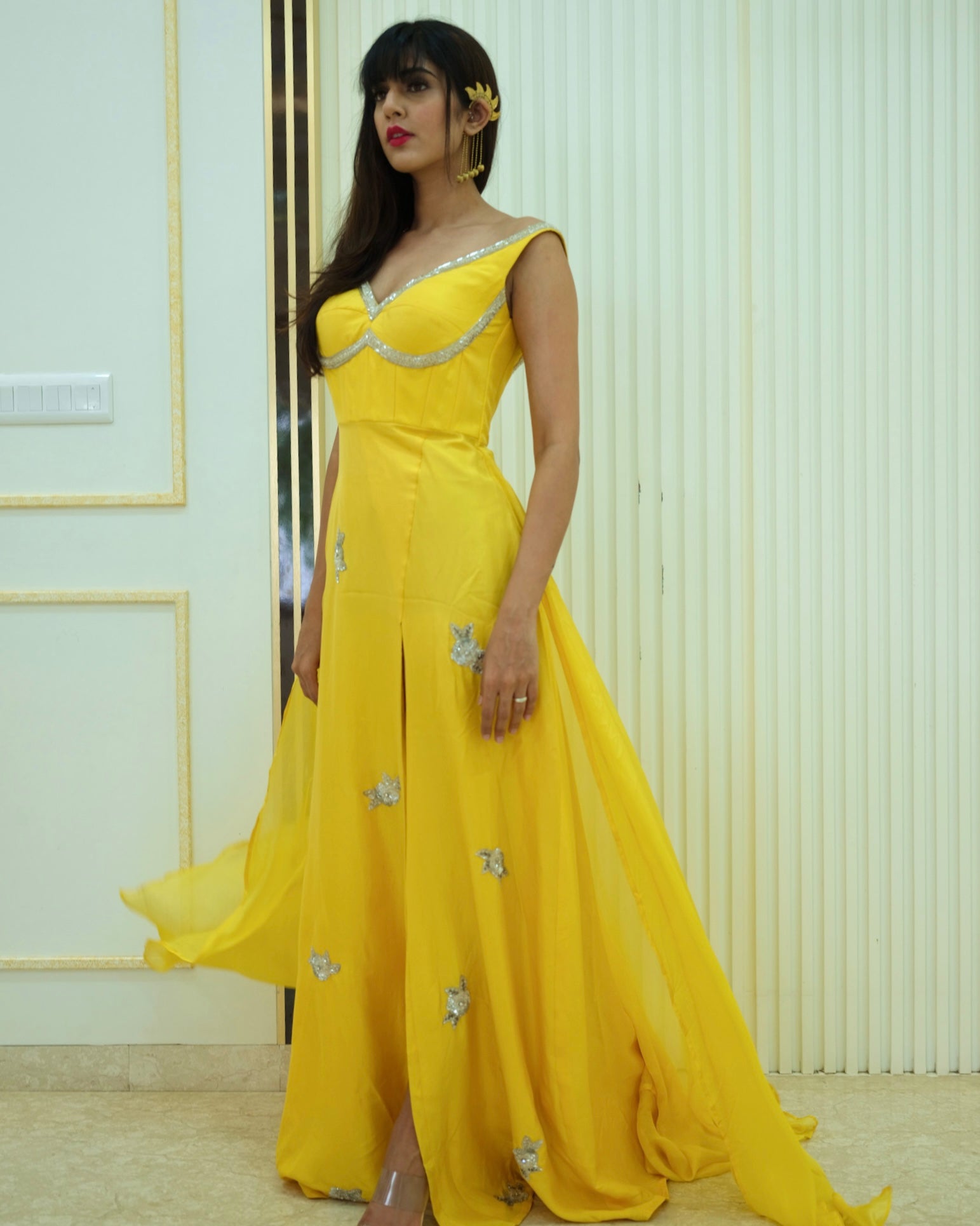 Woman wearing a yellow evening gown with floral details indoors.