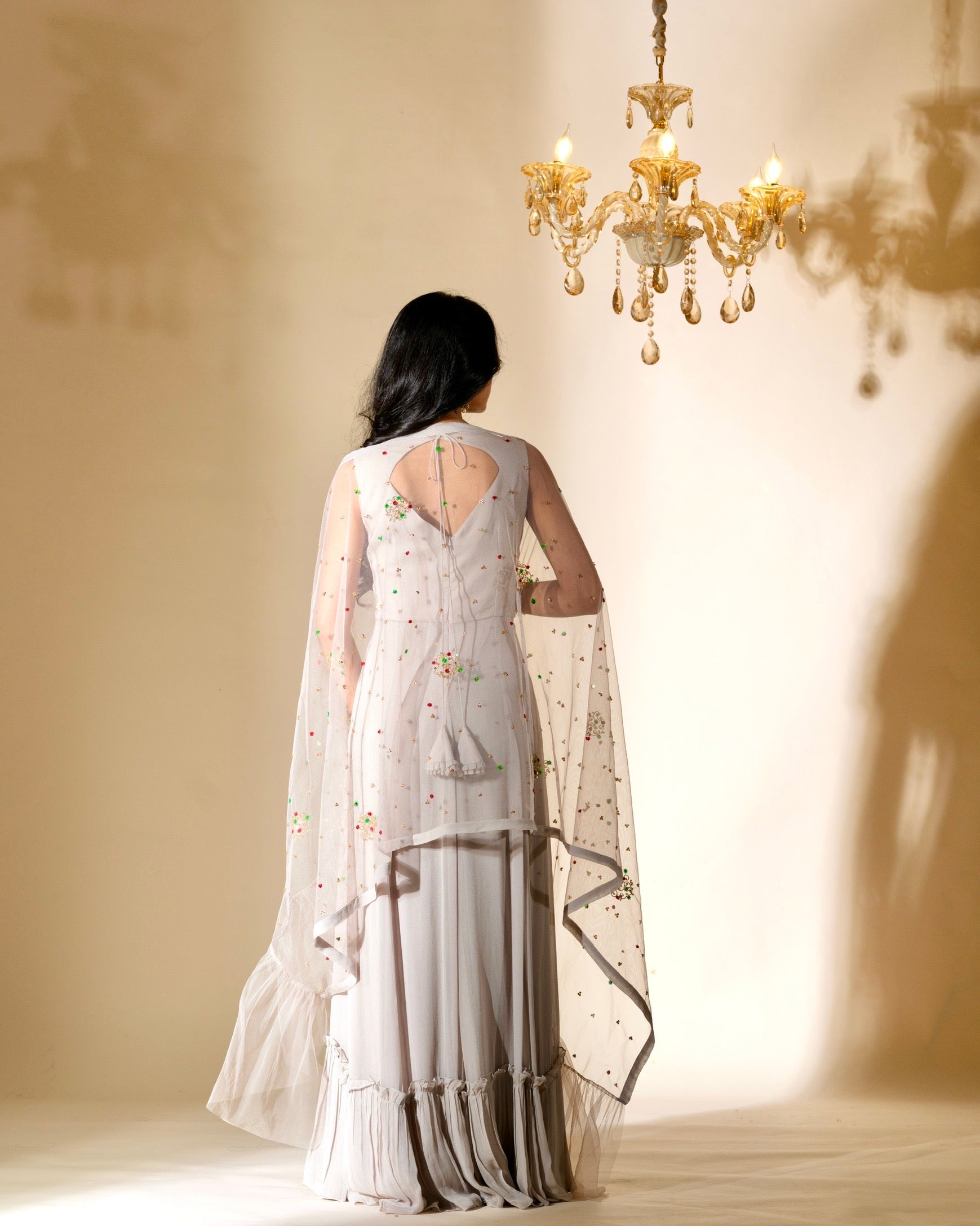 Woman in a white saree with a gold chandelier in the background