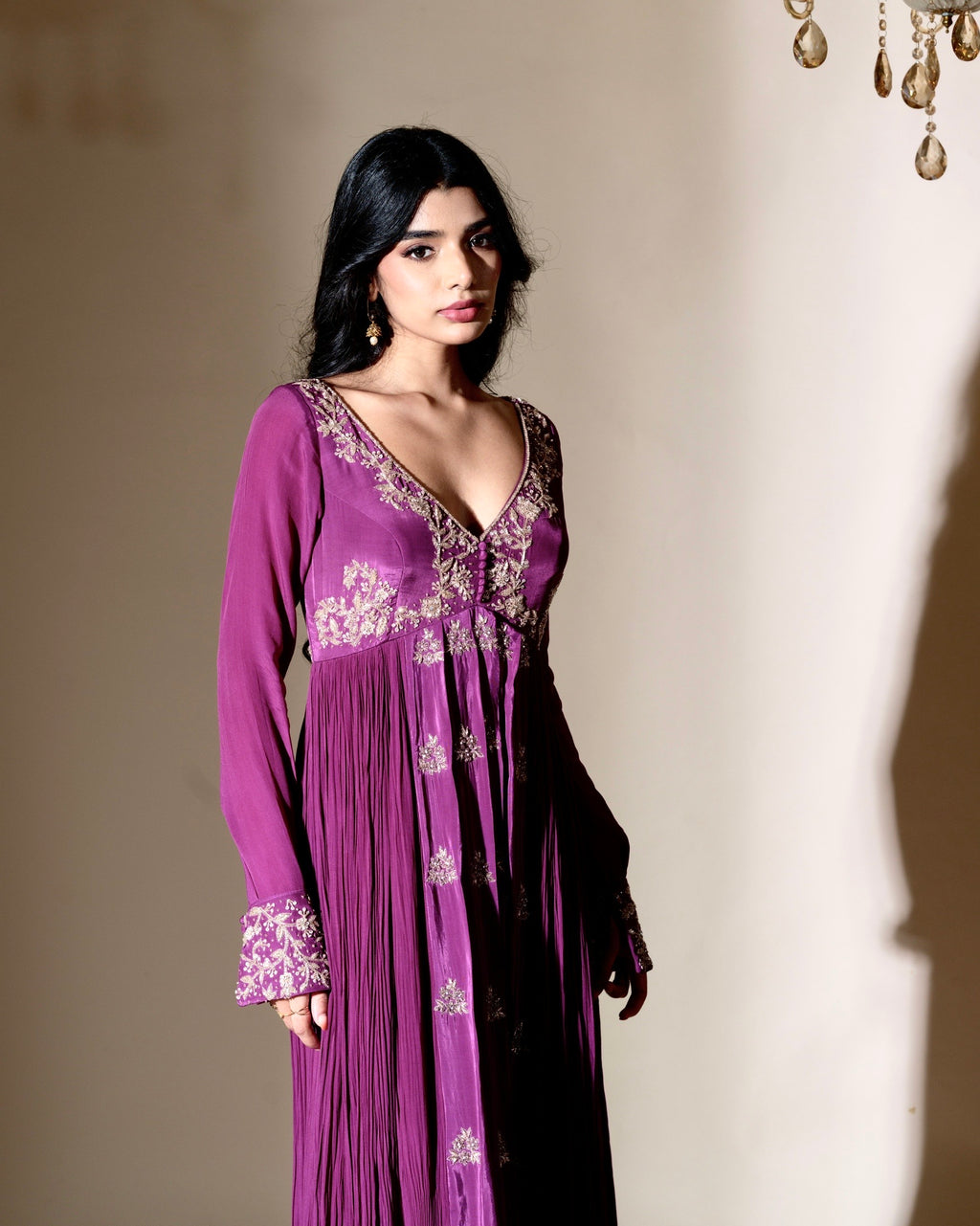 Woman wearing a purple dress with floral embroidery against a neutral background