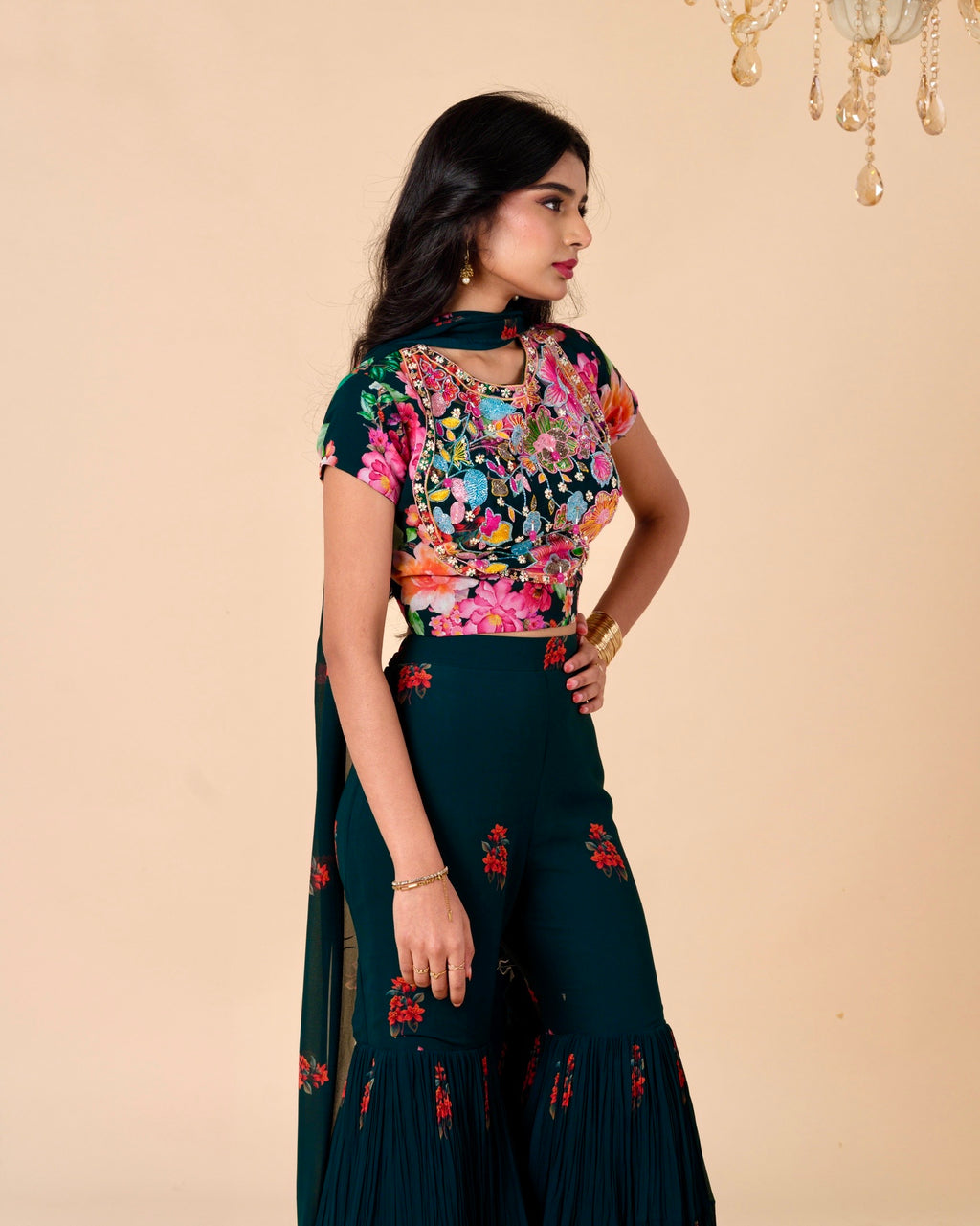 Woman wearing a dark green floral outfit against a beige background