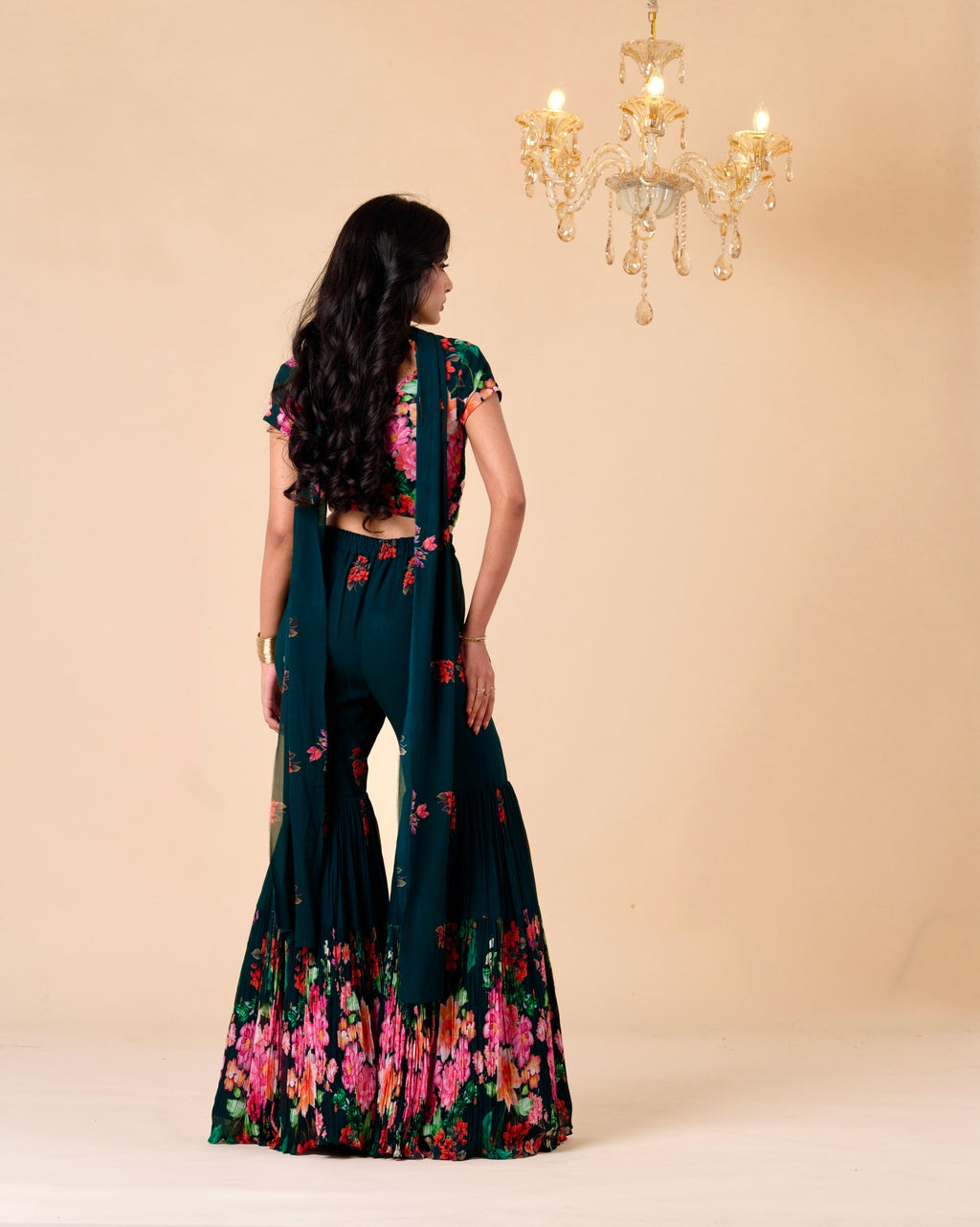 Woman wearing a dark green floral saree with a beige background
