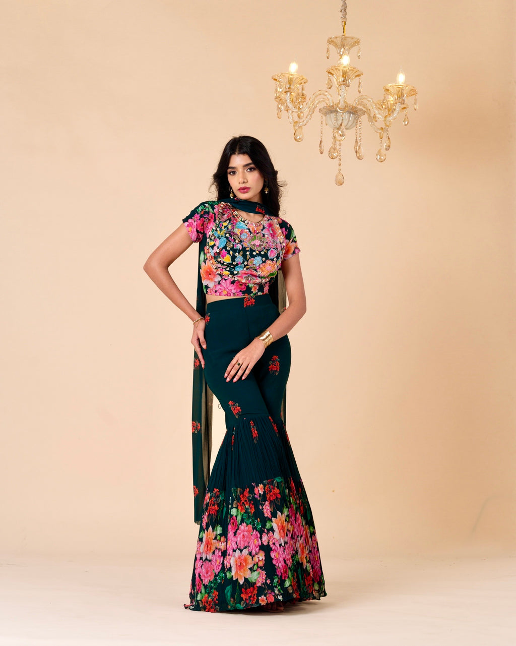 Woman wearing a floral dress with a beige background and chandelier.