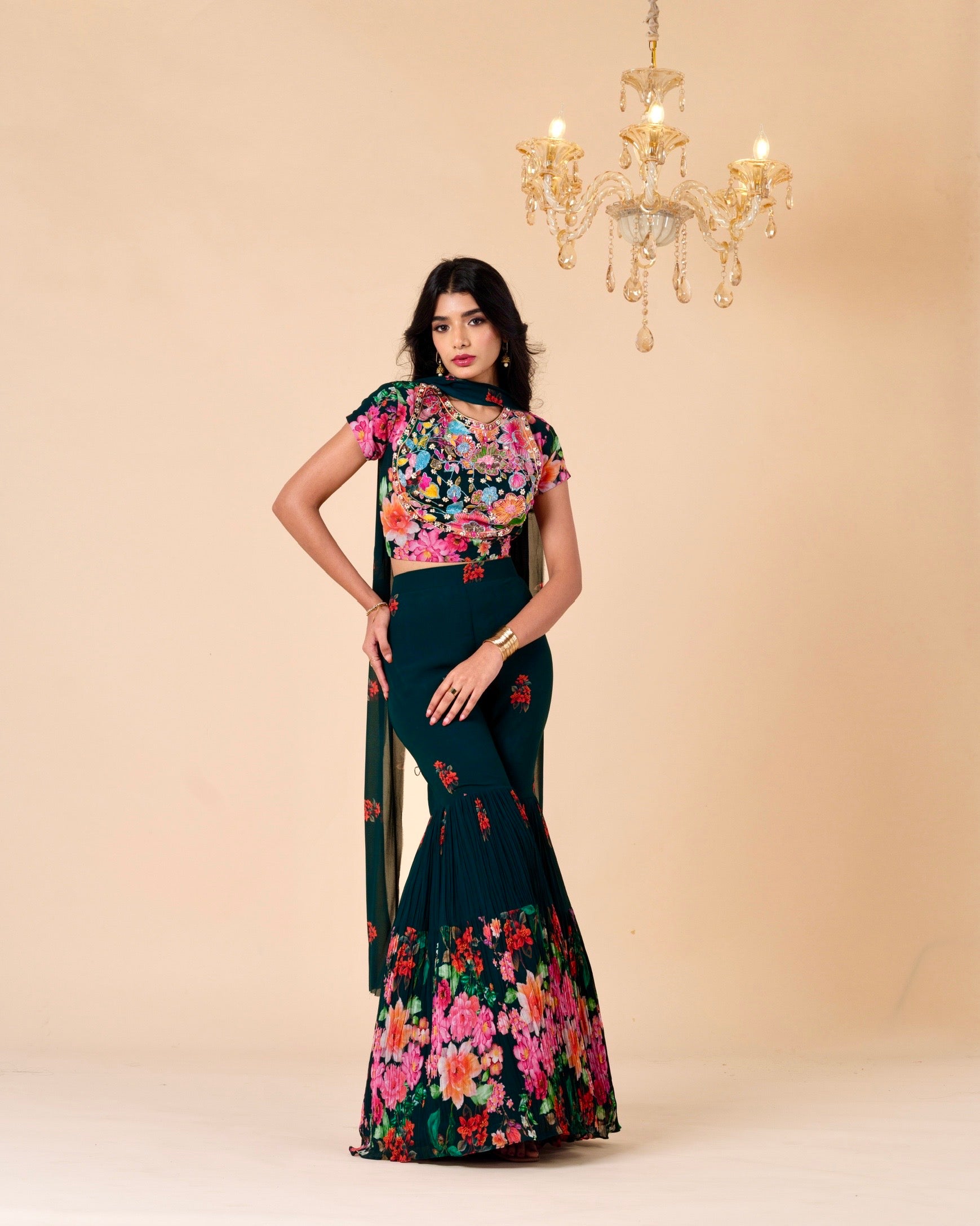 Woman wearing a floral dress with a beige background and chandelier.