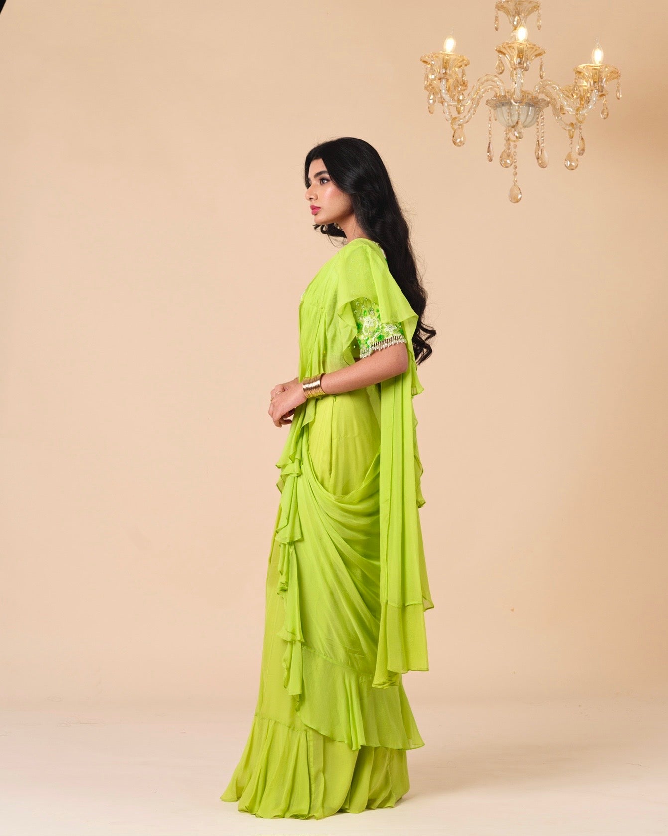 Woman wearing a bright green saree with a beige background