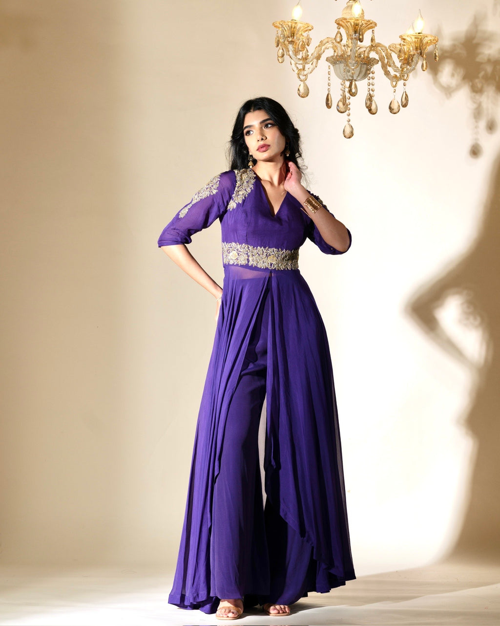 Woman wearing a purple evening gown with silver embellishments in a softly lit room.