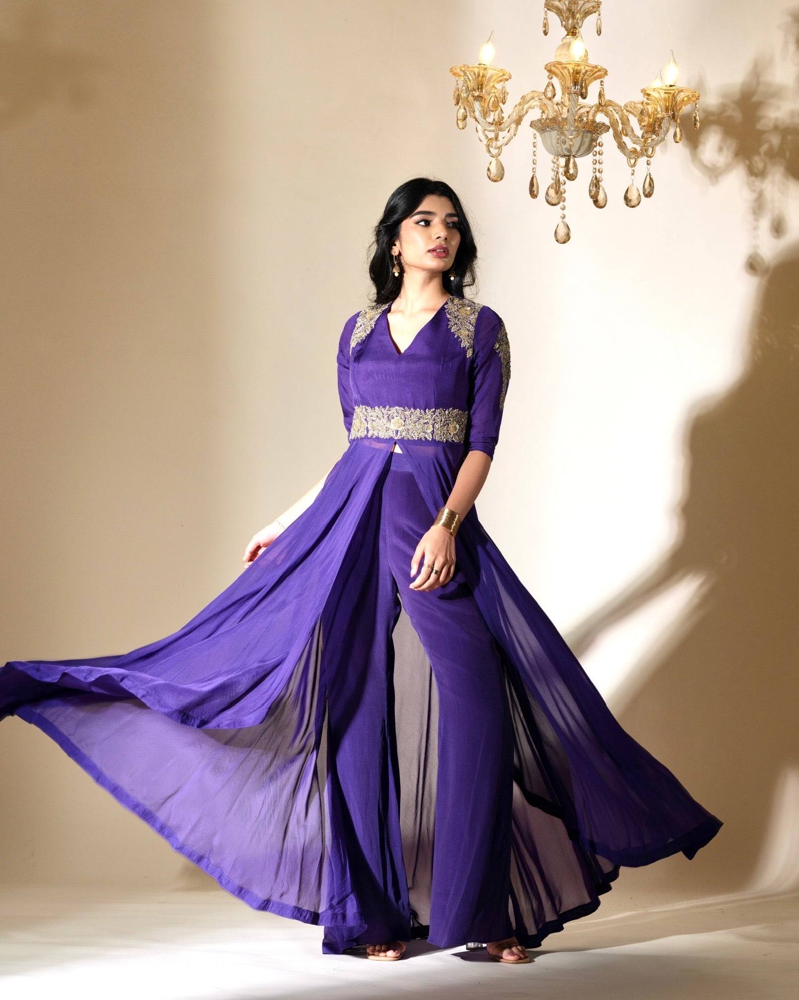 Woman wearing a long purple dress with a chandelier in the background