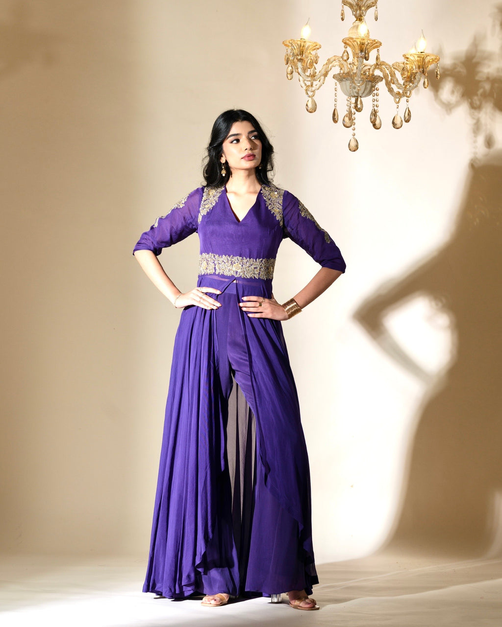 Woman wearing a purple dress with silver embellishments in a softly lit room.