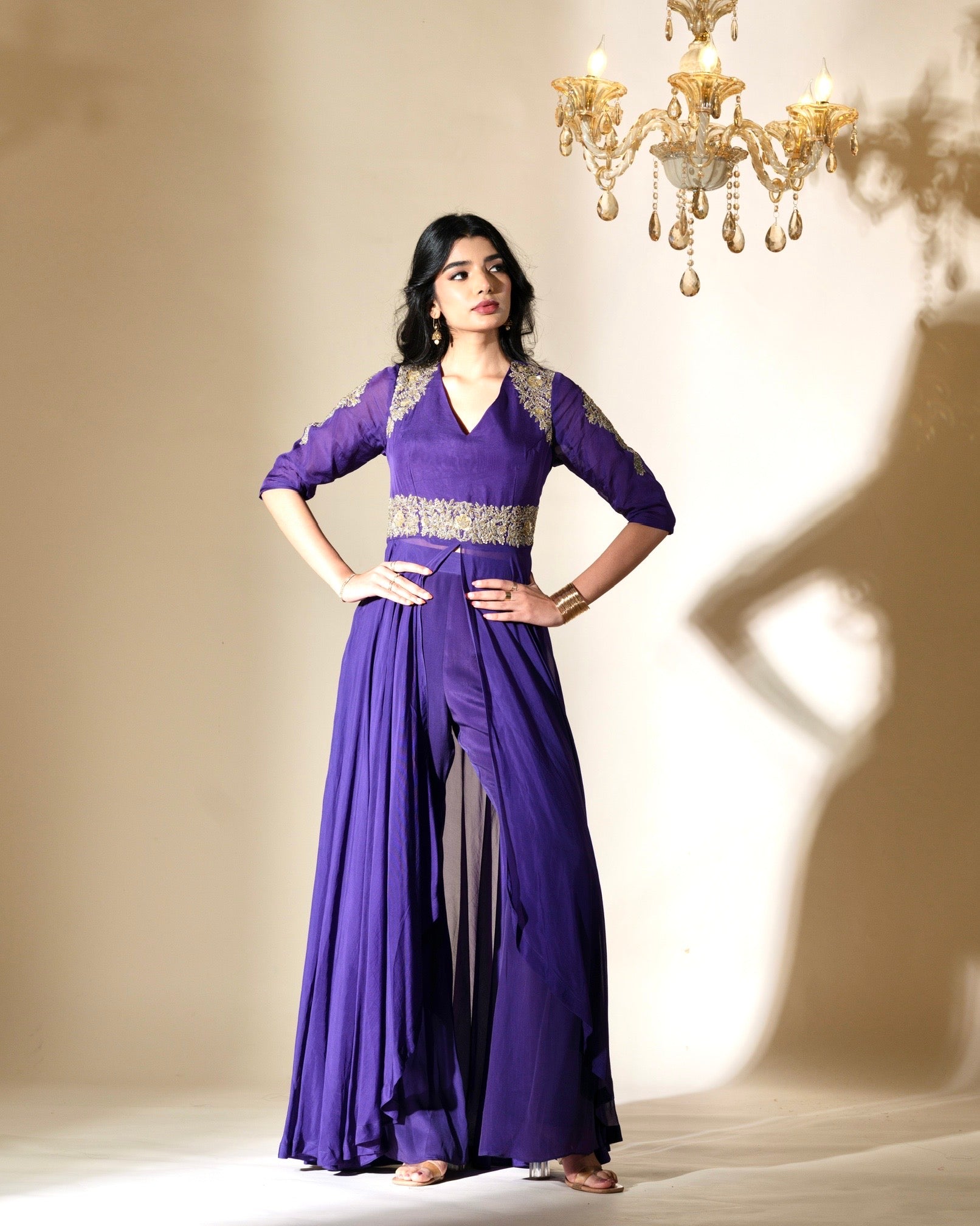 Woman wearing a purple dress with silver embellishments in a softly lit room.