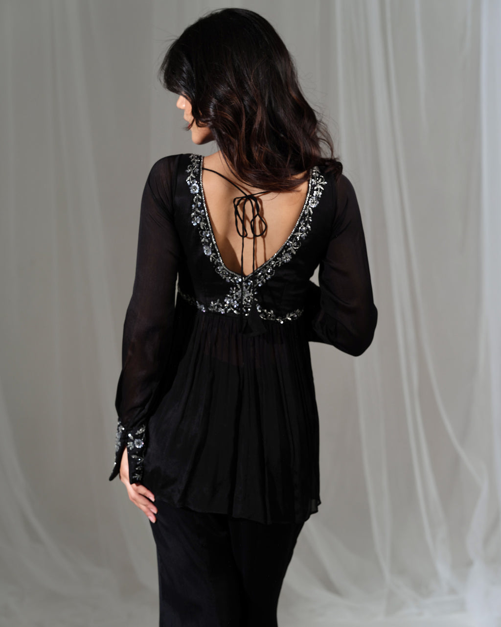 Black blouse with intricate back design on a plain background