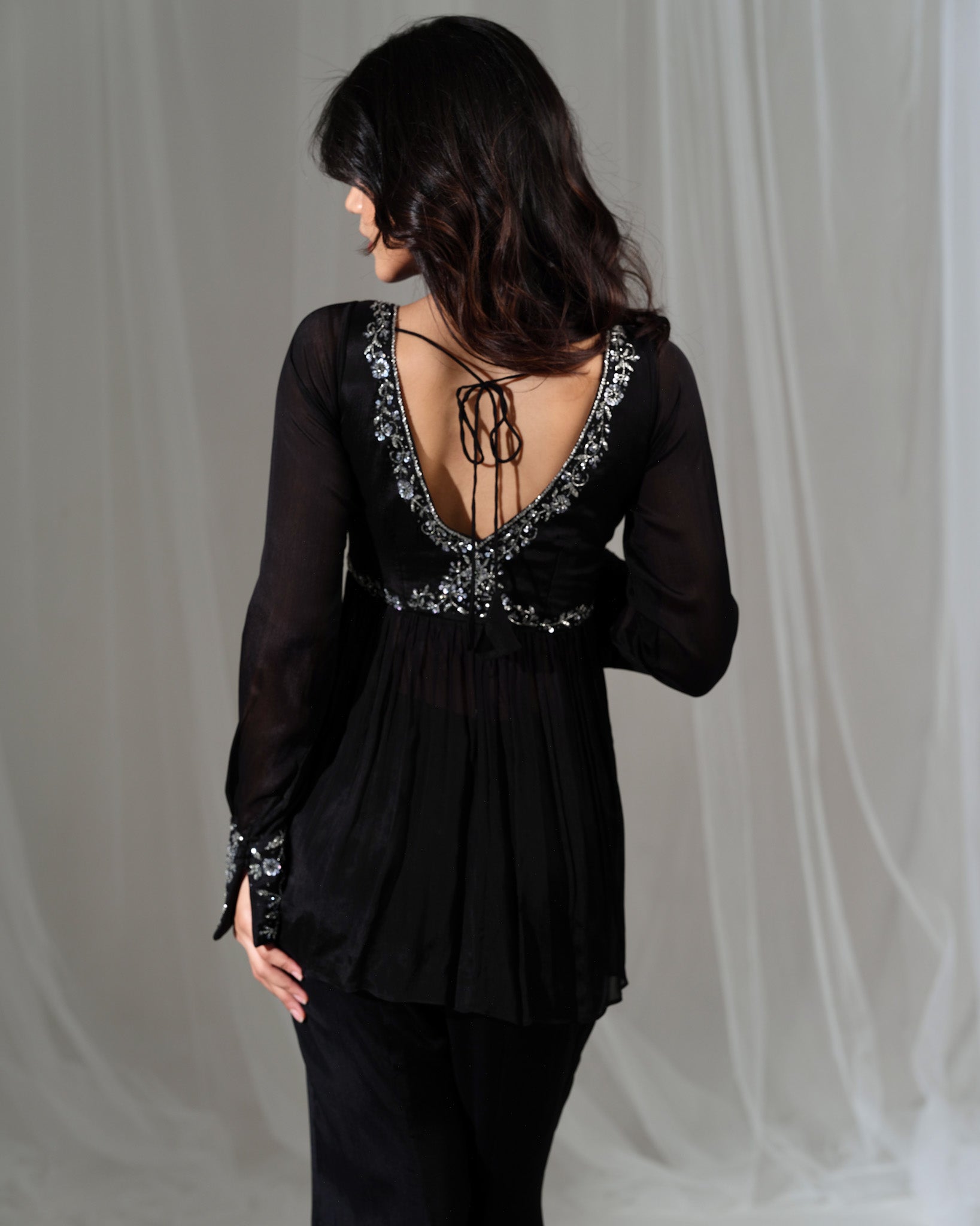Black blouse with intricate back design on a plain background