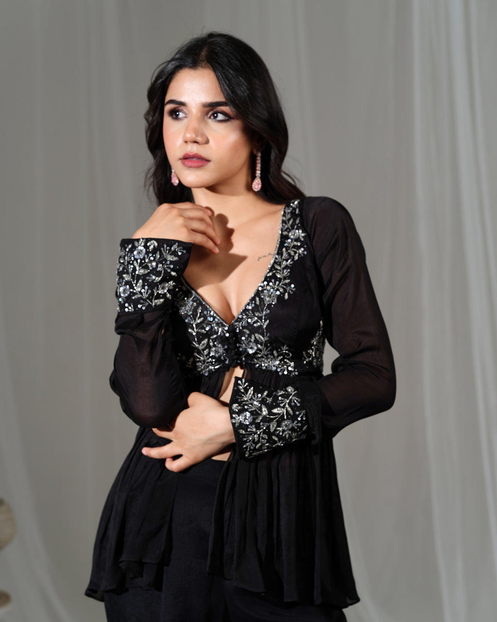 Woman wearing a black outfit with floral patterns against a plain background