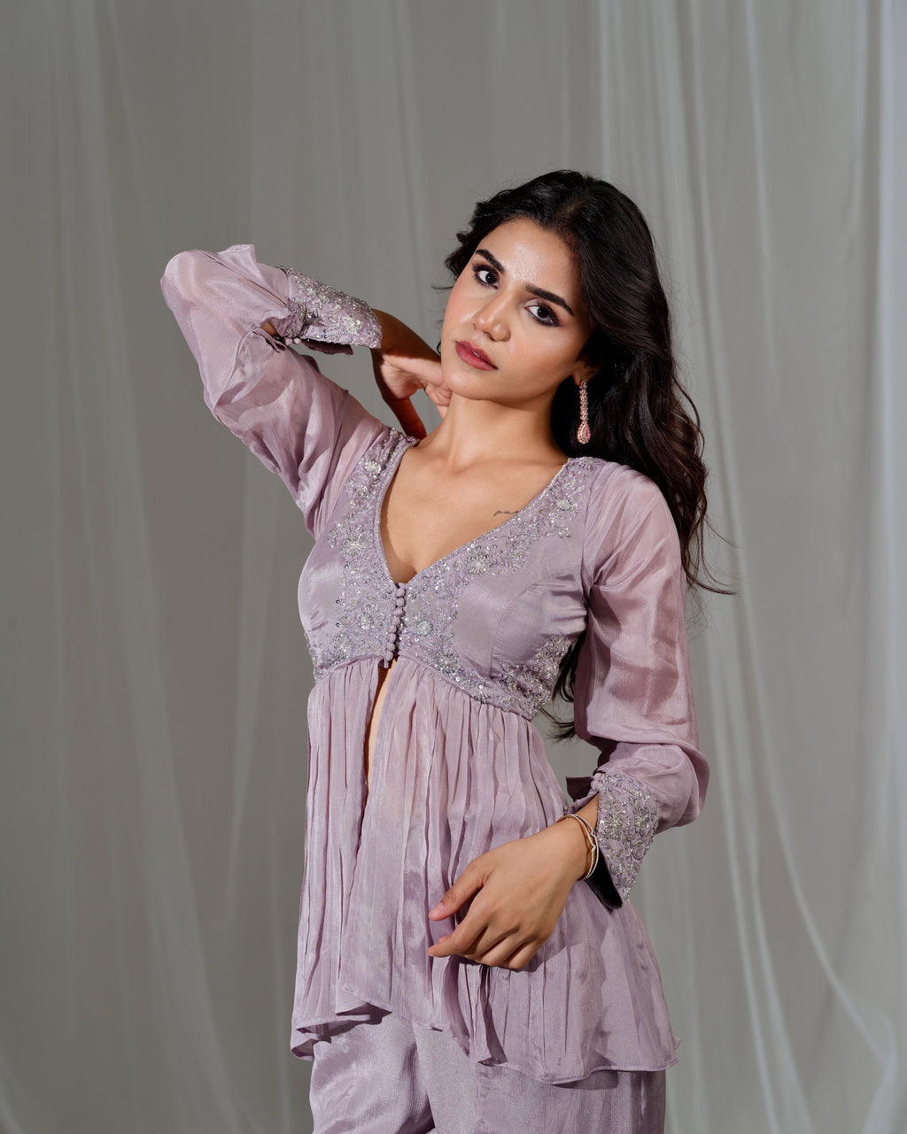 Woman wearing a light purple dress with lace details against a plain background