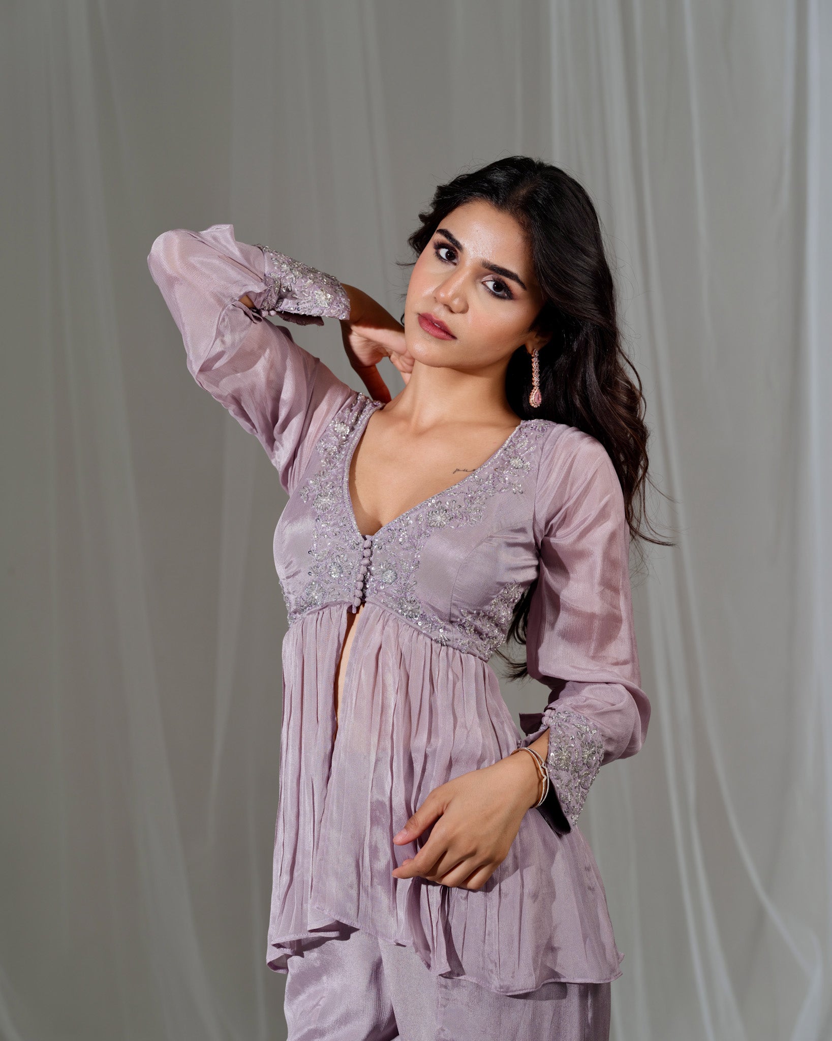 Woman wearing a light purple dress with lace details against a plain background